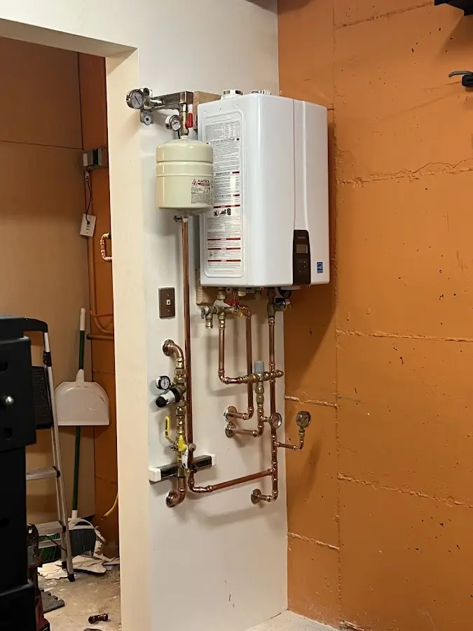 Plumbing technician inspecting water heater connections in Almena